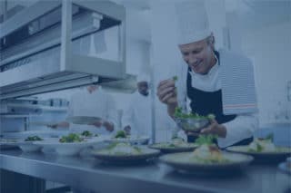 Smiling male chef working at kitchen with blue filter